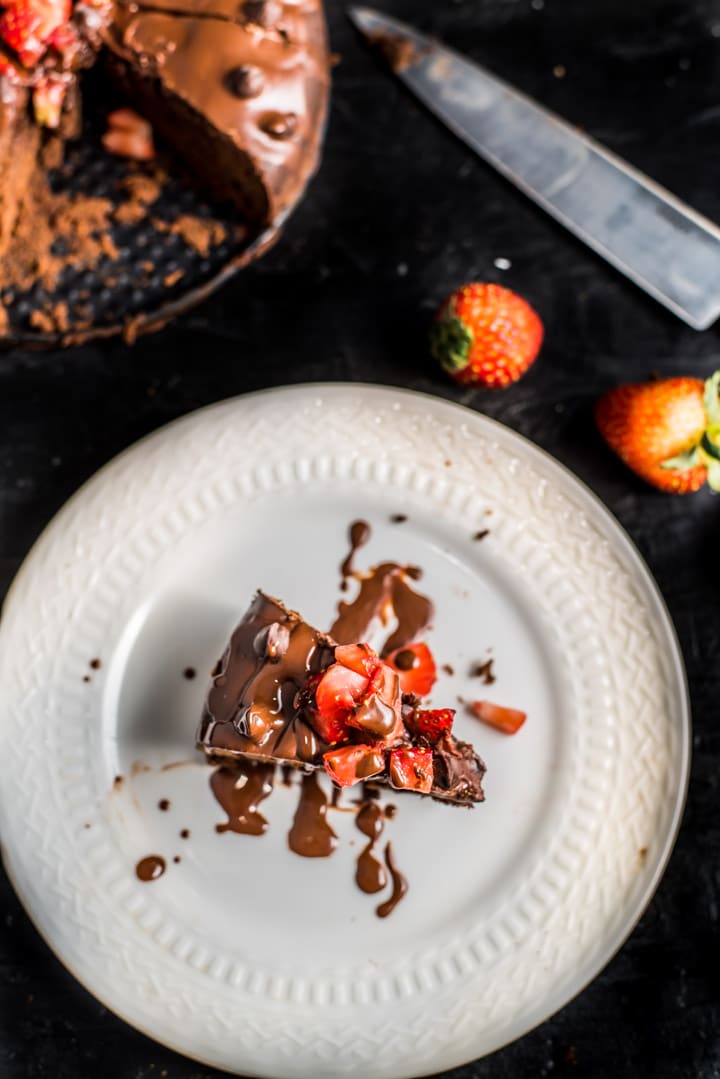 A white plate with a slice of instant pot brownies topped with strawberries.