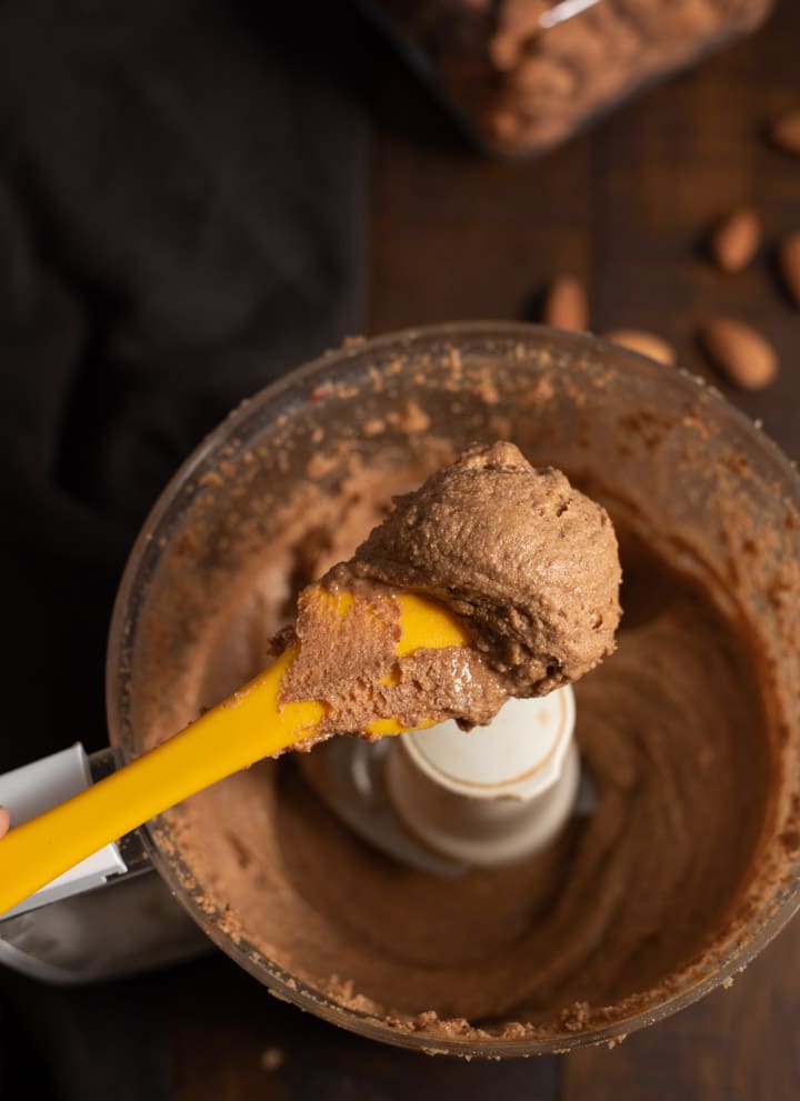 A close up of almond butter scooped using a yellow spatula