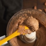 A closeup shot of almond butter scooped in a yellow spatula