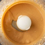 Creamy peanut butter in a food processor with the words One Ingredient Peanut Butter at the bottom.