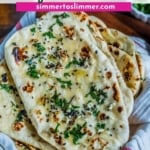 A stack of fresh garlic naan with cilantro on a with dish towel with the words Restaurant Style Garlic Naan at the top.
