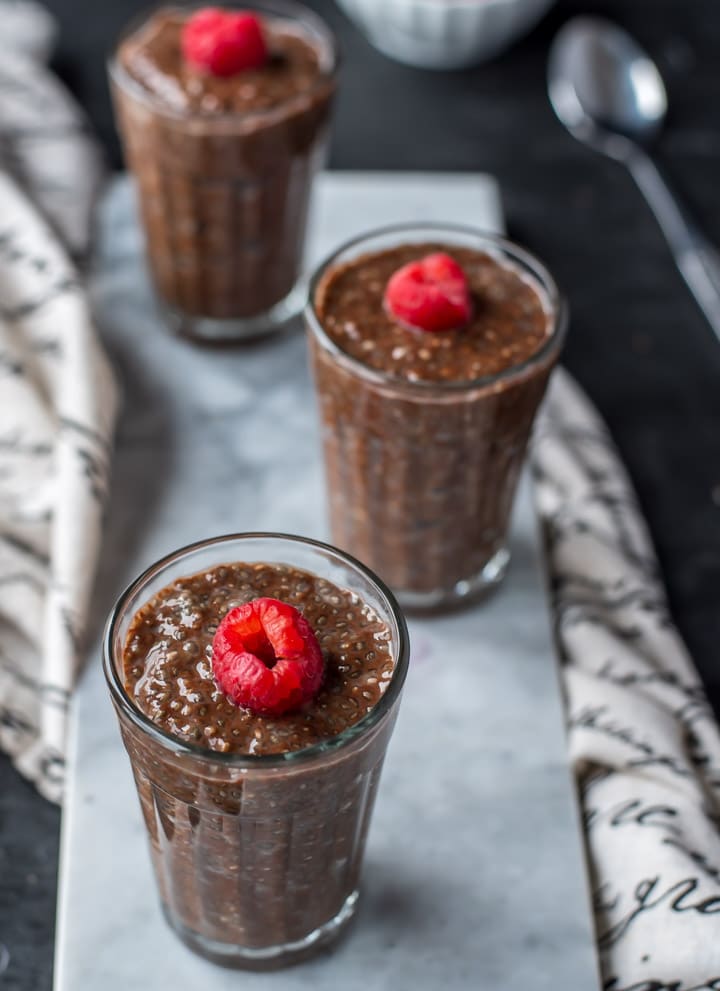 Three glassed filled with Chocolate Chia Pudding placed on a marble tray