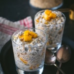 Two glassed filled with Mango overnight oats placed in a black plate