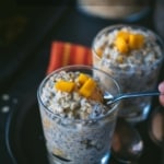 Two glassed filled with Mango overnight oats placed in a black plate