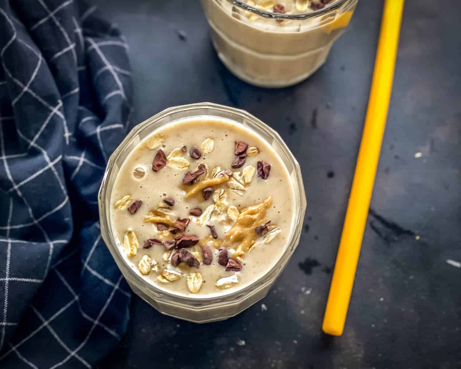 An overhead shot of Peanut Butter Banana Smoothie drizzled with cacao nibs and peanut butter