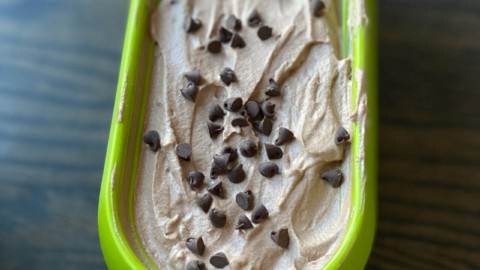A green ice cream tub with double chocolate ice cream and chocolate chips on top.