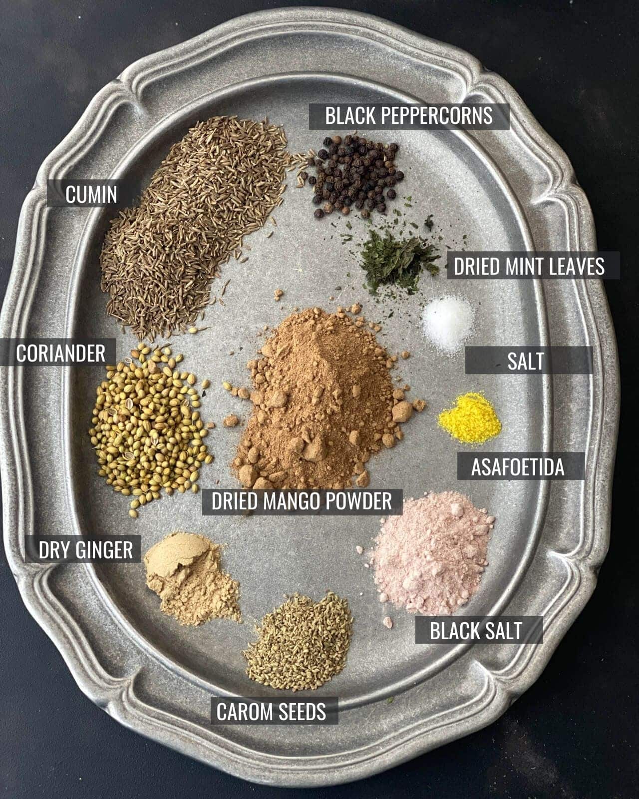 All 10 ingredients used in chaat masala laid out in a pewter plate