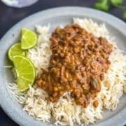 Lamgar ki dal served with cumin rice in a grey plate with 3 slices of lime on the side