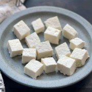 A light blue plate with chunks of fresh cut paneer with the words Instant Pot Homemade Paneer at the top.