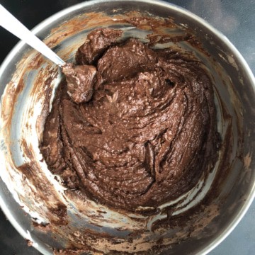 A silver mixing bowl with chocolate zucchini bread batter mixed together.