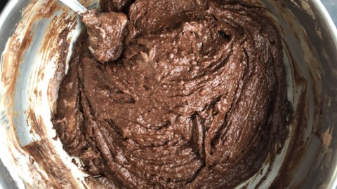 A silver mixing bowl with chocolate zucchini bread batter mixed together.