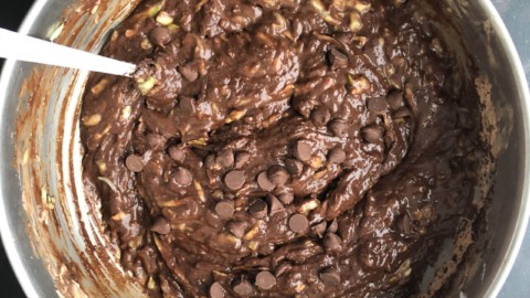 A silver mixing bowl with chocolate zucchini bread batter after adding the chocolate chips.