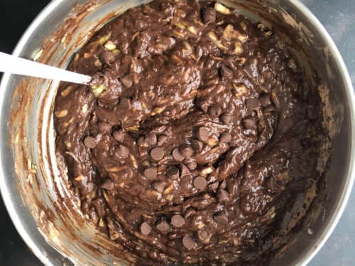 A silver mixing bowl with chocolate zucchini bread batter after adding the chocolate chips.