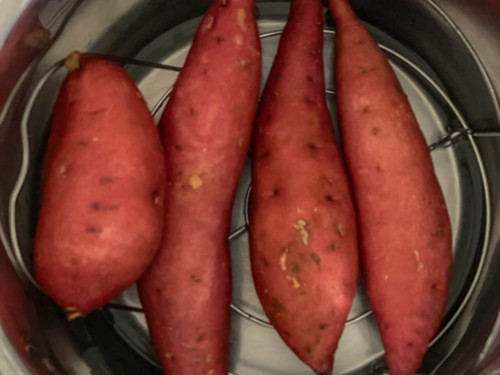 Four sweet potatoes on a trivet inside the instant pot.