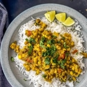 The words Instant Pot at the top in white with the words Whole Moong Dal Curry below in yellow with a picture of moong dal curry on top of rice with a few limes on a grey plate.
