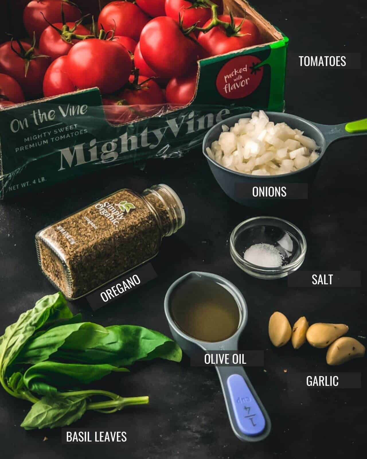 Ingredients laid out for marinara sauce on a grey counter with the different ingredients labeled.