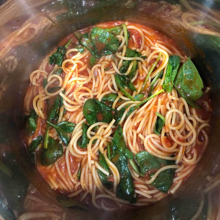 Spinach added to the cooked pasta and sauce inside the instant pot.