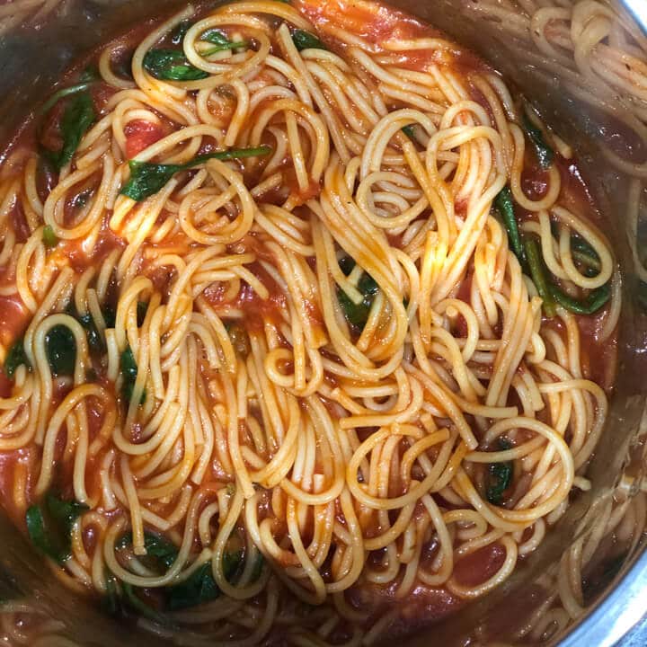 Cooked vegetarian instant pot pasta with spinach in the steel insert.