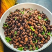 Black chickpeas (kala chana) served in a white bowl with a multi color napkin on the side