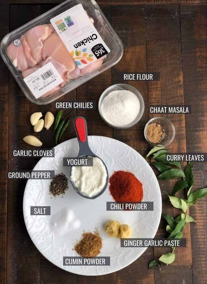 The ingredients for Chicken 65 on a wooden table with labels telling the name of each ingredient.