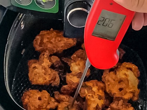 A thermometer checking the temperature of chicken 65 after frying.