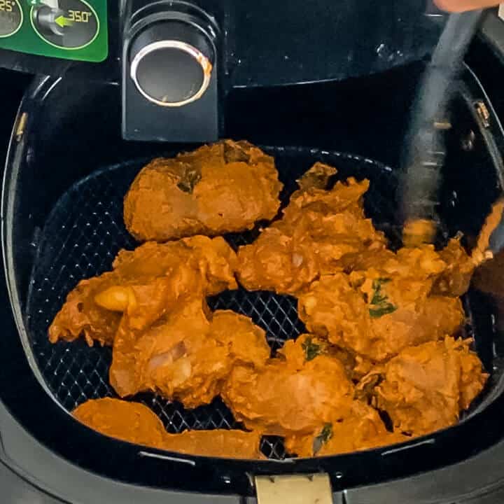 Chicken in the air fryer basket in a single layer.