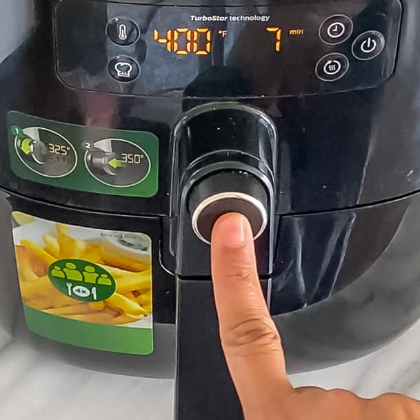 A hand starting the air fryer for 7 minutes.
