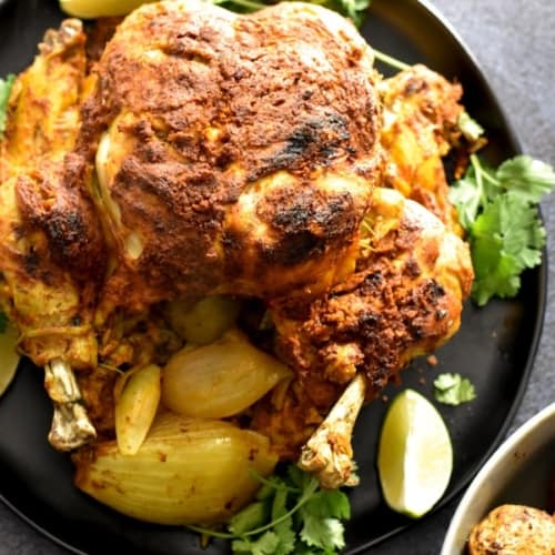 Whole Tandoori chicken served on a black plate