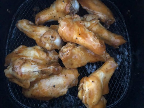 Chicken wings in the air fryer after being coated with sauce.