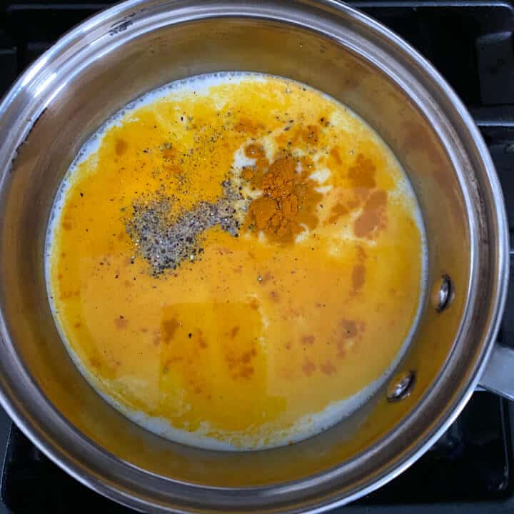 The ingredients for Golden Milk in a saucepan on the stove before boiling and before stirring.