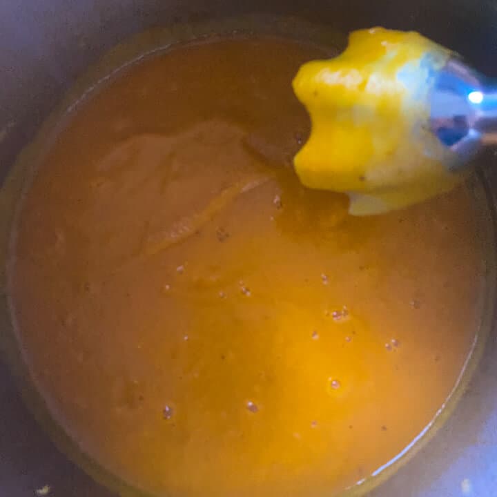 An immersion blender after pureeing the butternut squash soup.