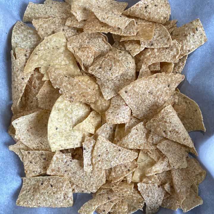 A parchment paper lined baking sheet topped with tortilla chips.