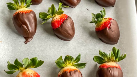 A parchment paper lined baking sheet with chocolate dipped strawberries cooling.