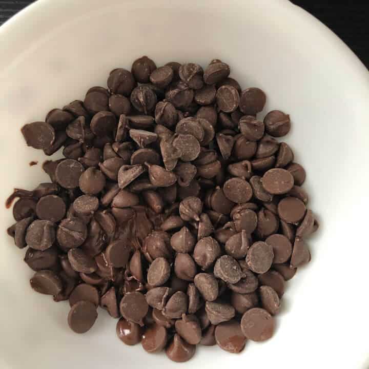 A white bowl with chocolate chips before melting.