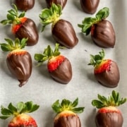 A parchment paper covered in chocolate dipped strawberries with the words homemade chocolate covered strawberries at the top.