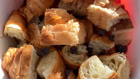 A white baking dish with chopped croissants and chocolate chips.