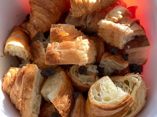 A white baking dish with chopped croissants and chocolate chips.
