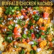 A sheet pan covered in parchment paper and topped with buffalo chicken nachos and the words Loaded Buffalo Chicken Nachos at the top.