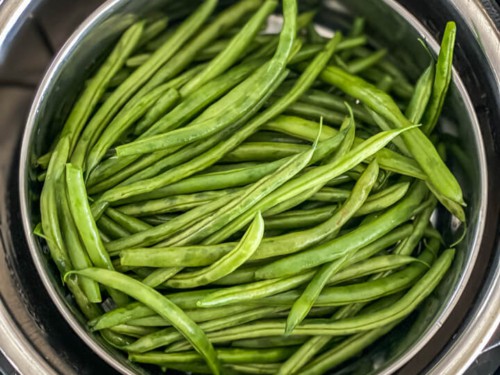 An instant pot with fresh green beans.