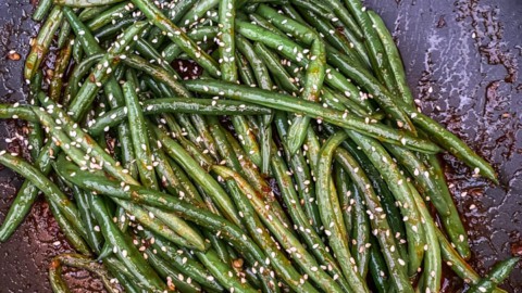 A skillet with asian-style green beans topped with sesame seeds.