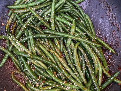 A skillet with asian-style green beans topped with sesame seeds.