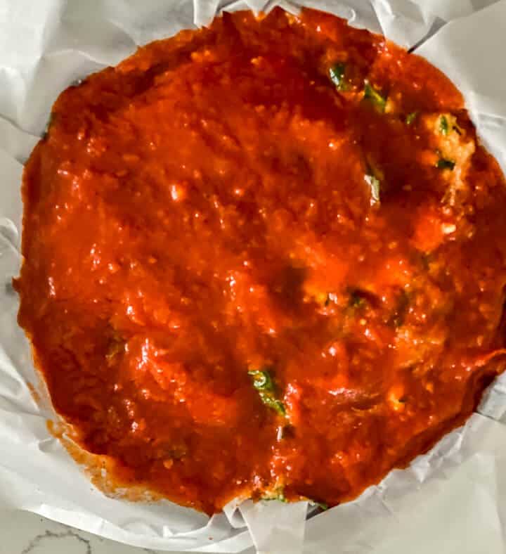 The final layer of marinara sauce on top of the springform pan lasagna.
