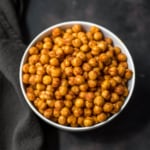 A white bowl with spicy roasted chickpeas on a black towel.