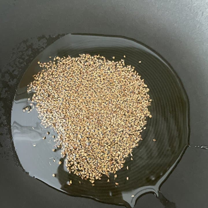 Oil and ajwain heating in the wok.