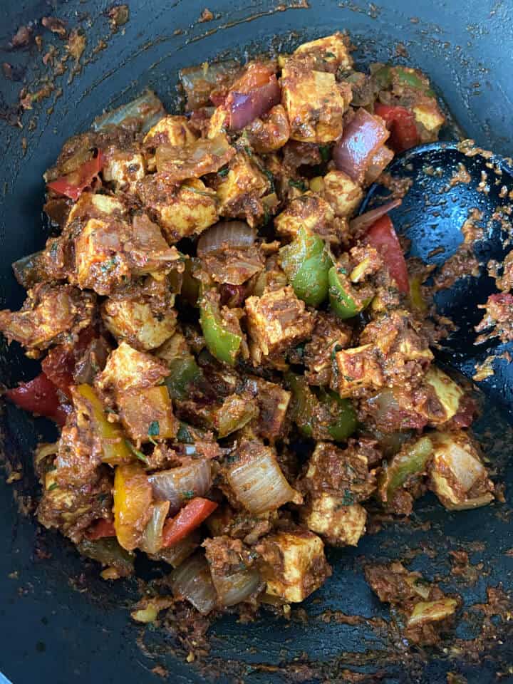 Paneer added to the wok with a spoon to the right.