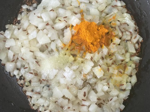 Onion and spices added to the wok with oil.