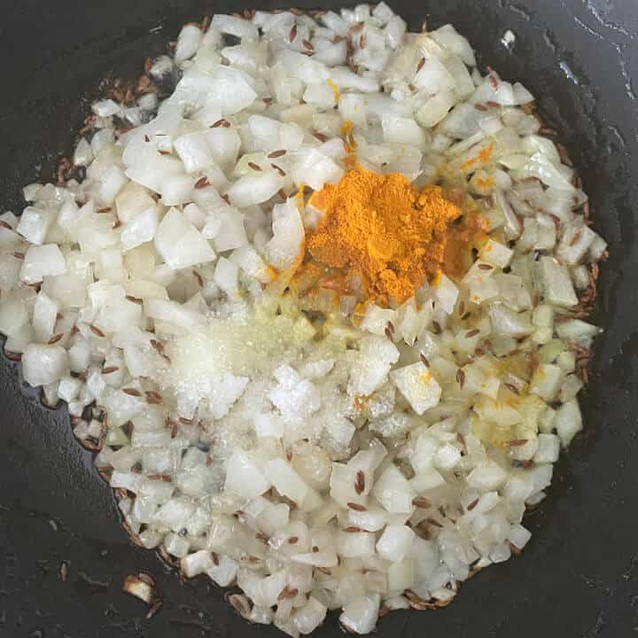 Onion and spices added to the wok with oil.