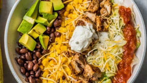 chipotle chicken burrito bowl in a white serving bowl with sour cream for lunch or dinner