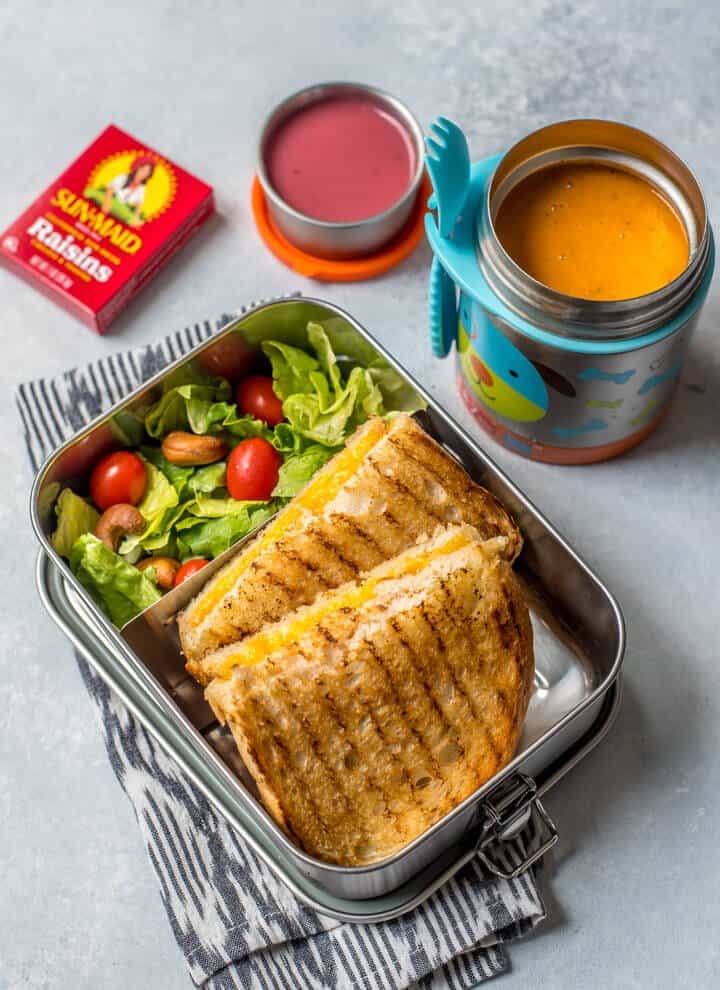 Grilled cheese sandwich served with salad in a steel container