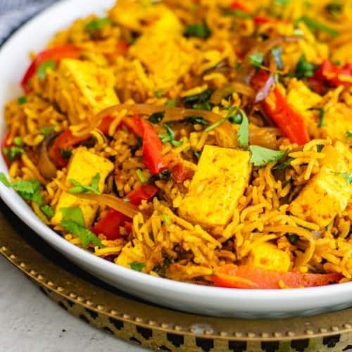 Biryani with paneer and bell peppers served in a white bowl